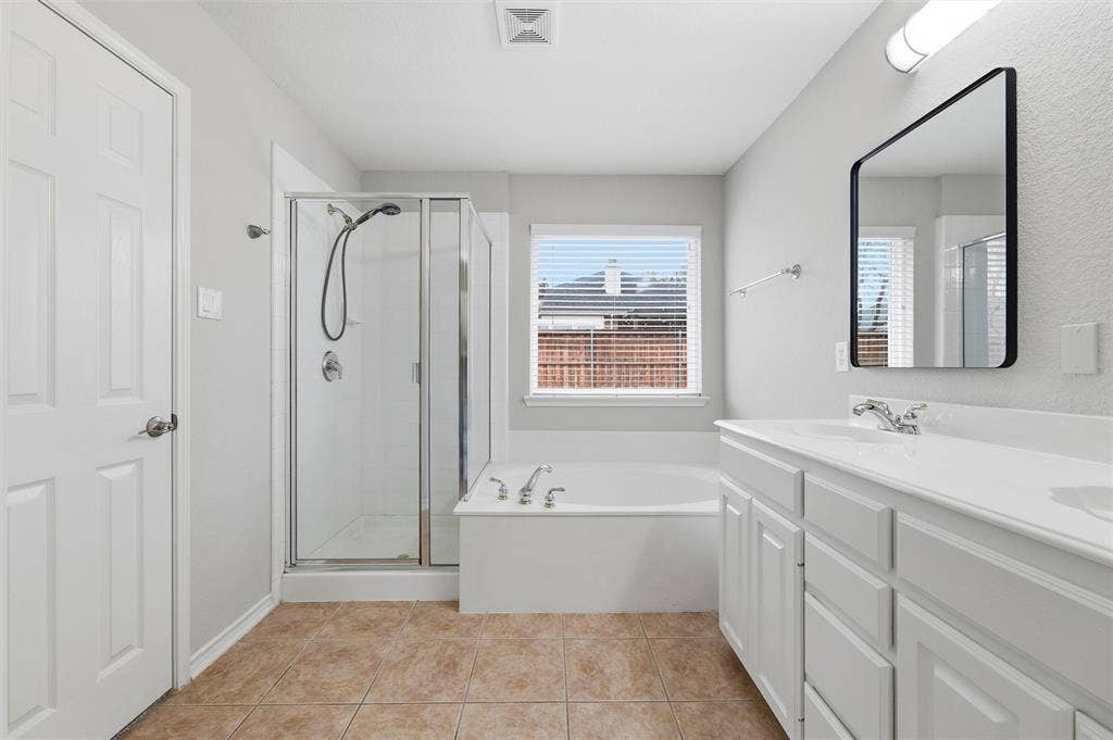 The Primary bathroom offers a soaking tub, separate glass-enclosed shower, and tile flooring.