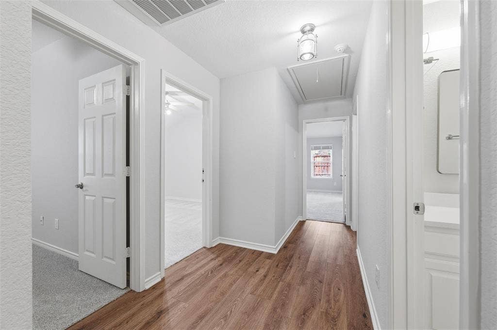 Well-lit hallway featuring new luxury vinyl plank flooring and fresh neutral finishes, connecting the main living areas to the private bedrooms.