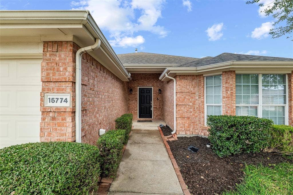 Covered front entry with brick surround and landscaped walkway, providing a welcoming arrival.