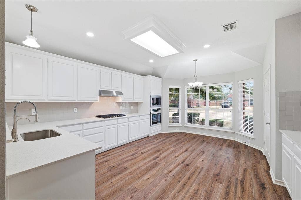 The beautifully refreshed kitchen showcases new quartz countertops, designer backsplash, freshly painted cabinetry, and stainless steel appliances.