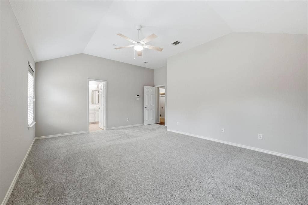 Another view of the primary bedroom highlights the generous room size, neutral color palette, and updated ceiling fan.
