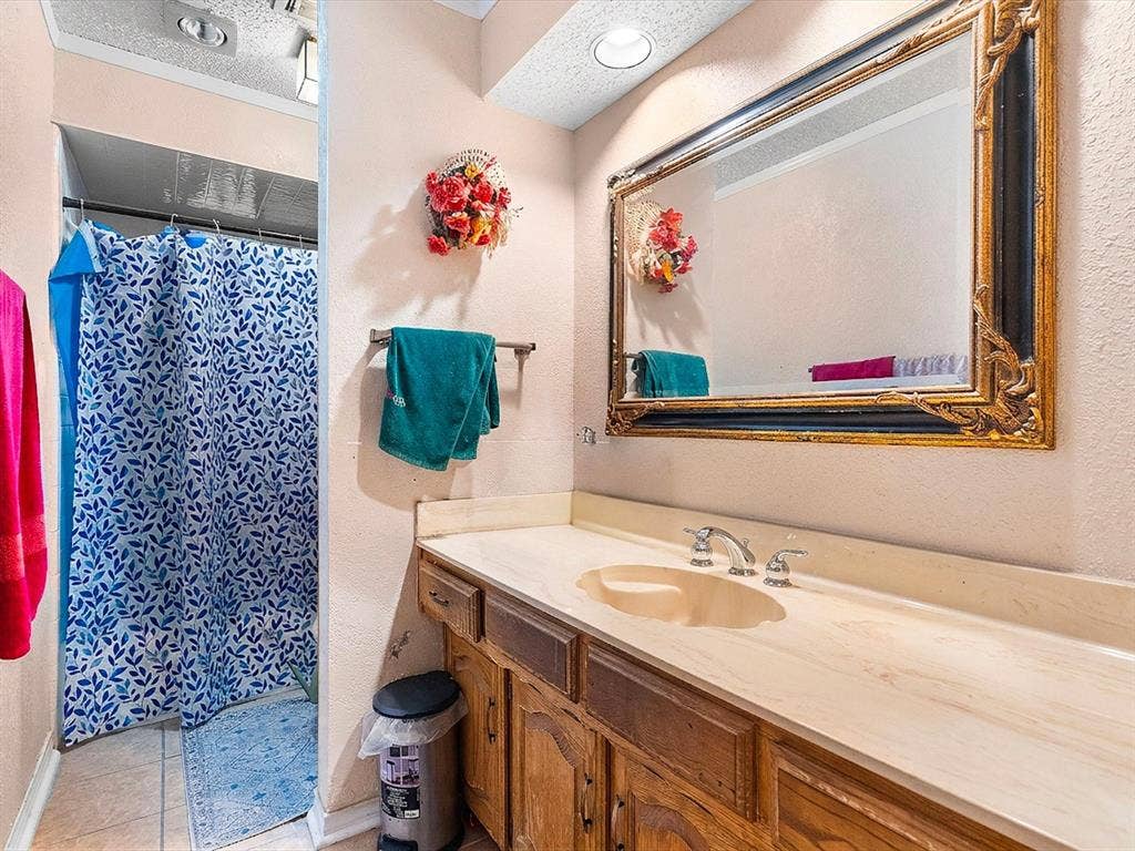 5818 Winding Woods Trail, Dallas, TX 75227 Bathroom featuring a vanity with a light-toned countertop, integrated sink, and an ornate framed mirror