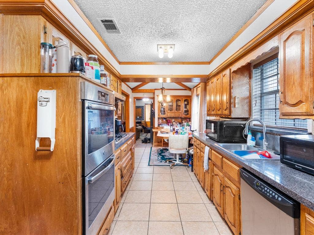 5818 Winding Woods Trail, Dallas, TX 75227 Galley kitchen featuring wood cabinetry, stainless steel double ovens, tile flooring, and a window for natural light