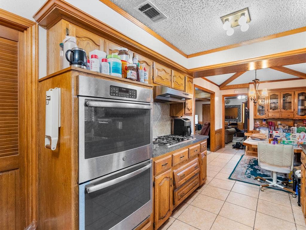 5818 Winding Woods Trail, Dallas, TX 75227 Double wall ovens, gas cooktop, wood cabinetry, tile flooring, and a ceiling-mounted light fixture