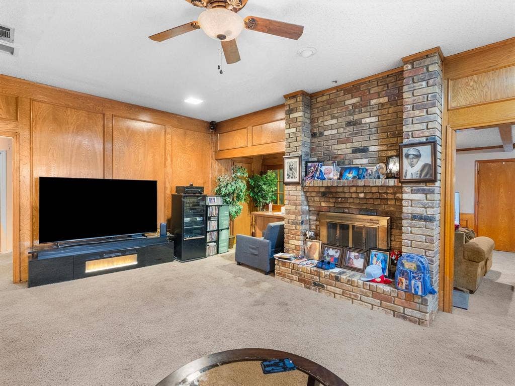 5818 Winding Woods Trail, Dallas, TX 75227 Brick fireplace with a brass-finish insert, wood paneling, and a ceiling fan
