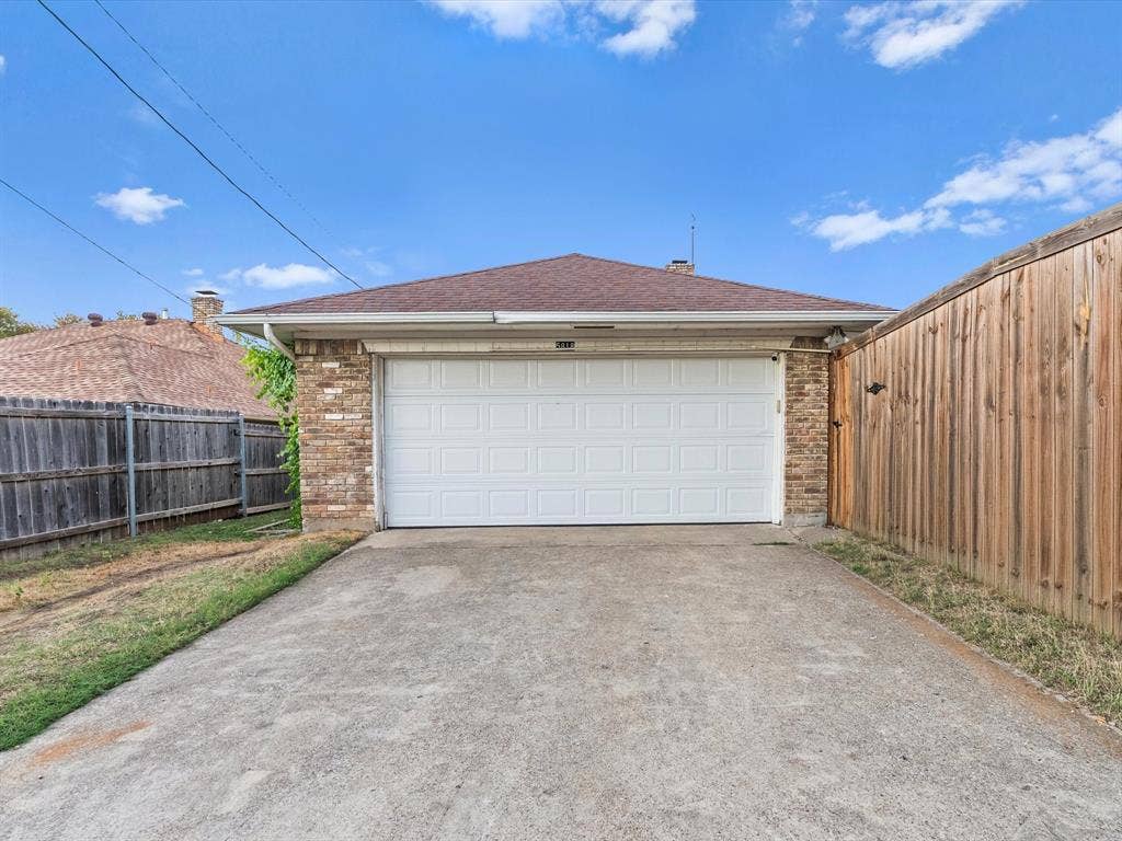 5818 Winding Woods Trail, Dallas, TX 75227 Attached garage with a white panel door, brick facade, and concrete driveway