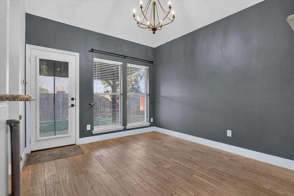 1825 Bachman Court, Plano, TX 75075 Vaulted ceilings, wood-finish flooring, charcoal-toned walls, decorative metal chandelier, and full-light exterior door