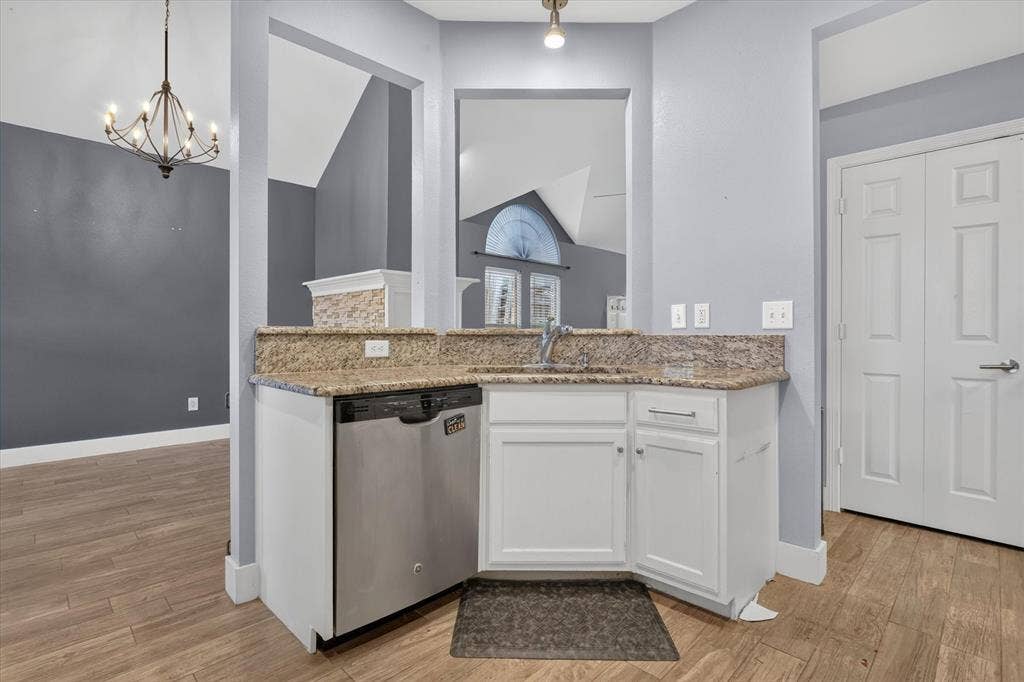1825 Bachman Court, Plano, TX 75075 Kitchen area featuring wood-finish flooring, white cabinetry, stone-finish countertops, stainless steel dishwasher, and metal-finish faucet