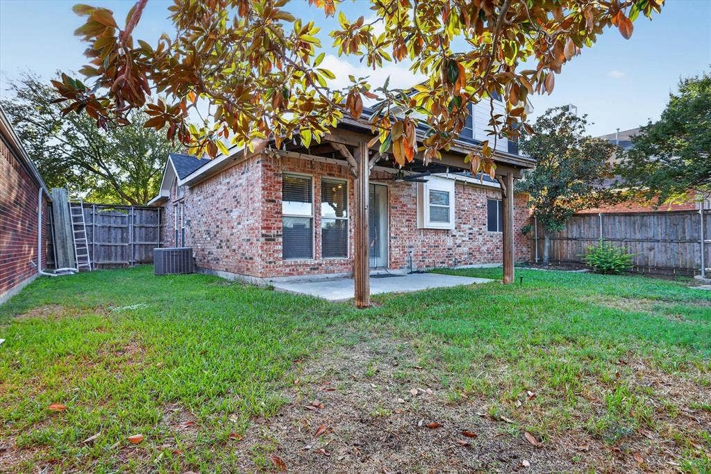 1825 Bachman Court, Plano, TX 75075 Brick exterior featuring a covered patio with wood support beams, concrete flooring, and a fenced backyard