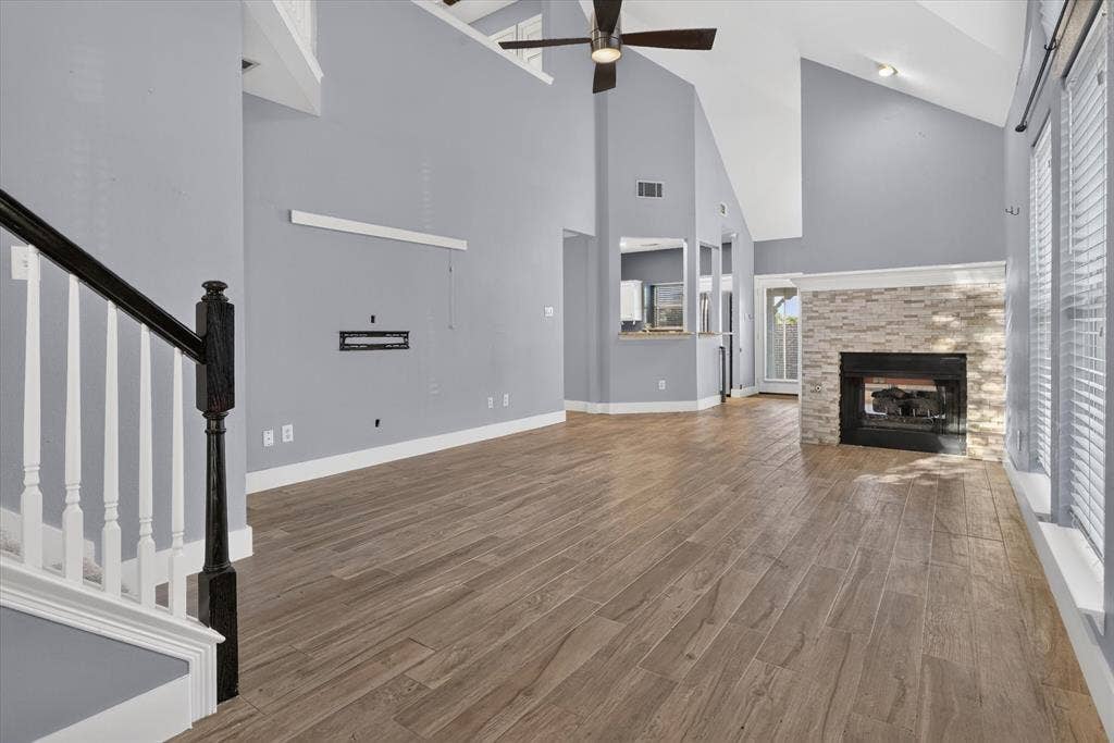 1825 Bachman Court, Plano, TX 75075 Vaulted ceilings, wood-finish flooring, stone-surround fireplace, ceiling fan, and wooden staircase railing