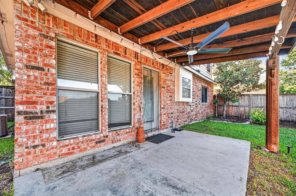 1825 Bachman Court, Plano, TX 75075 Expansive concrete patio with a wood-beamed overhead structure, integrated ceiling fan, and brick exterior