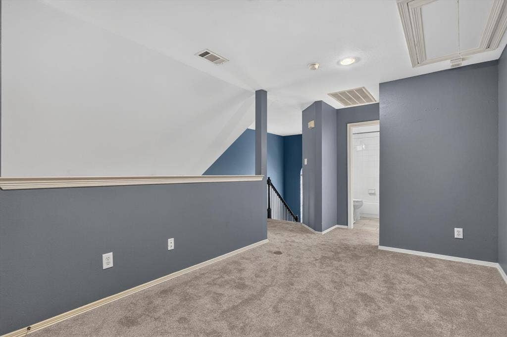 1825 Bachman Court, Plano, TX 75075 Neutral-toned wall-to-wall carpeting, vaulted ceiling with integrated recessed lighting, and a partial wall featuring a decorative chair rail