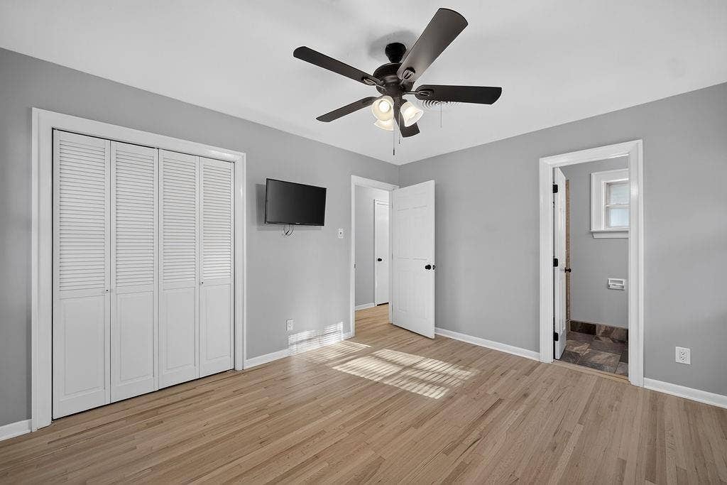 9112 Clearwater Drive, Dallas, TX 75243 Light wood-finish flooring, white louvered bifold closet doors, ceiling fan with integrated lighting, and gray wall paint