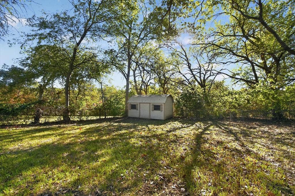 9112 Clearwater Drive, Dallas, TX 75243 Expansive lawn with mature trees and a detached shed