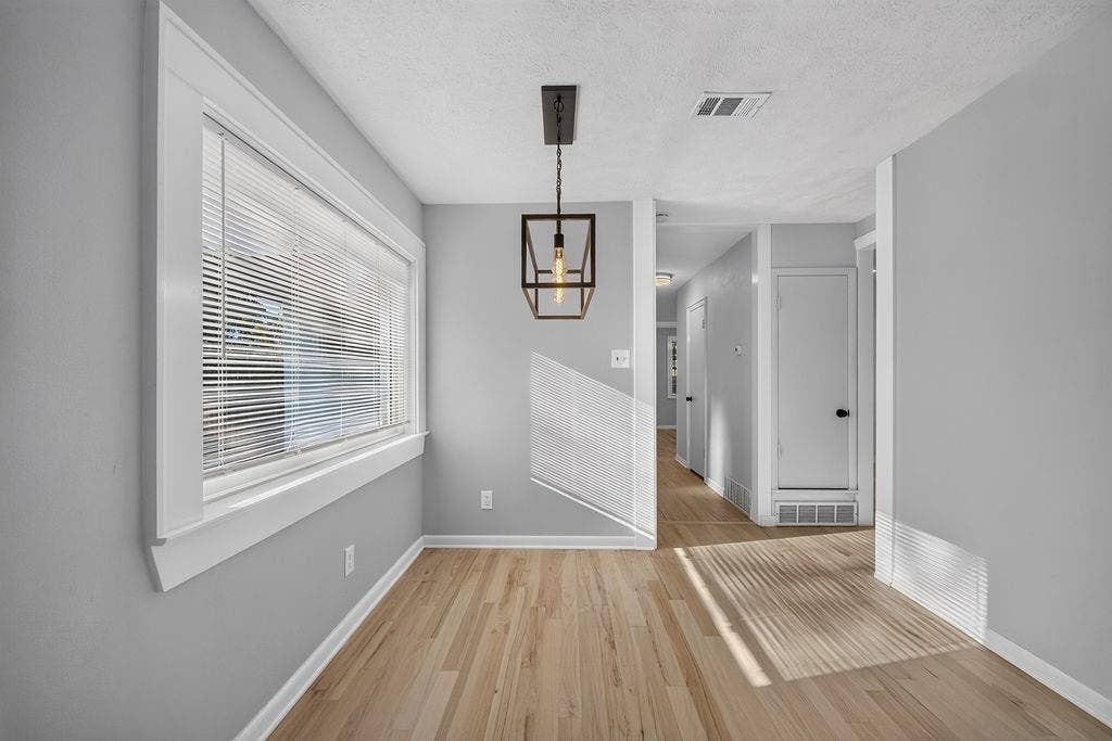 9112 Clearwater Drive, Dallas, TX 75243 Full-height grey cabinetry with matte black hardware, stainless steel refrigerator, recessed lighting, wood-finish flooring, and a modern ceiling light fixture