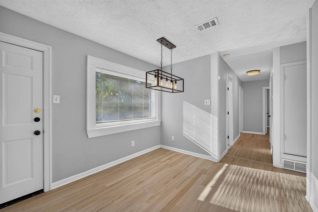 9112 Clearwater Drive, Dallas, TX 75243 Light wood-finish flooring, a contemporary black metal chandelier, and a white paneled door