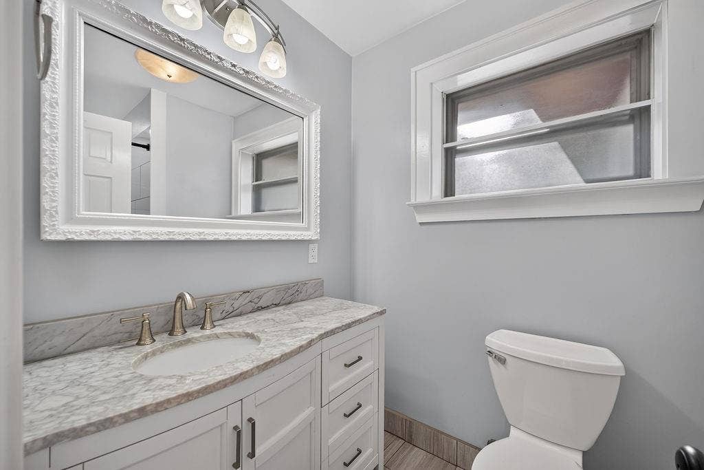 9112 Clearwater Drive, Dallas, TX 75243 White shaker vanity with a stone countertop, undermount sink, and brushed nickel faucet