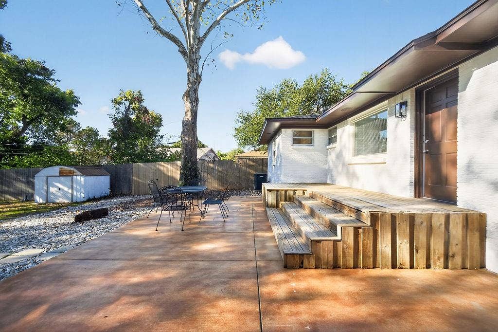 9112 Clearwater Drive, Dallas, TX 75243 Expansive concrete patio with a tiered wood deck, privacy fencing, and exterior storage shed