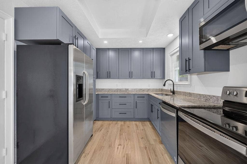9112 Clearwater Drive, Dallas, TX 75243 Kitchen featuring U-shaped cabinetry, granite-finish countertops, stainless steel appliances, wood-finish flooring, and recessed lighting