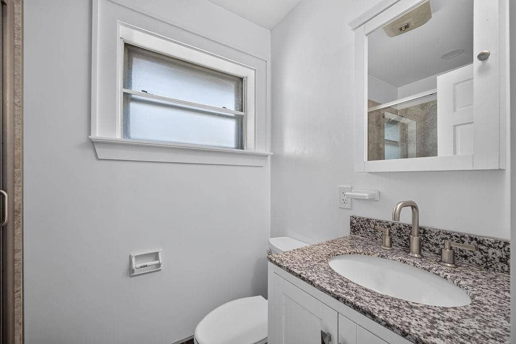 9112 Clearwater Drive, Dallas, TX 75243 Bathroom featuring a white vanity with a speckled countertop, undermount sink, and brushed nickel fixtures