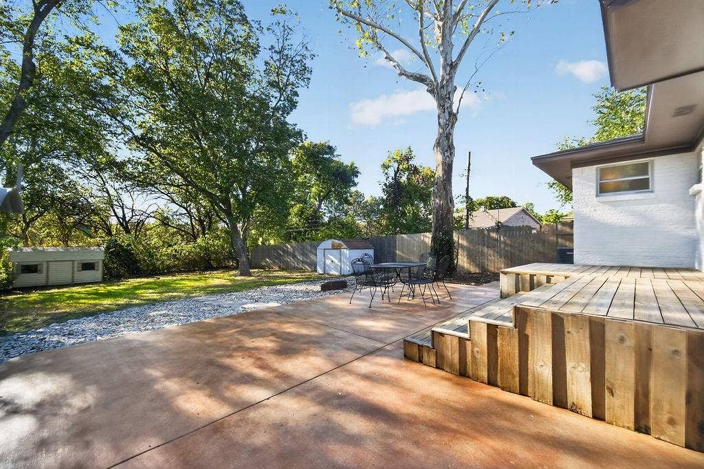 9112 Clearwater Drive, Dallas, TX 75243 Outdoor living space featuring a wood-plank deck, concrete patio, gravel pathway, and mature trees