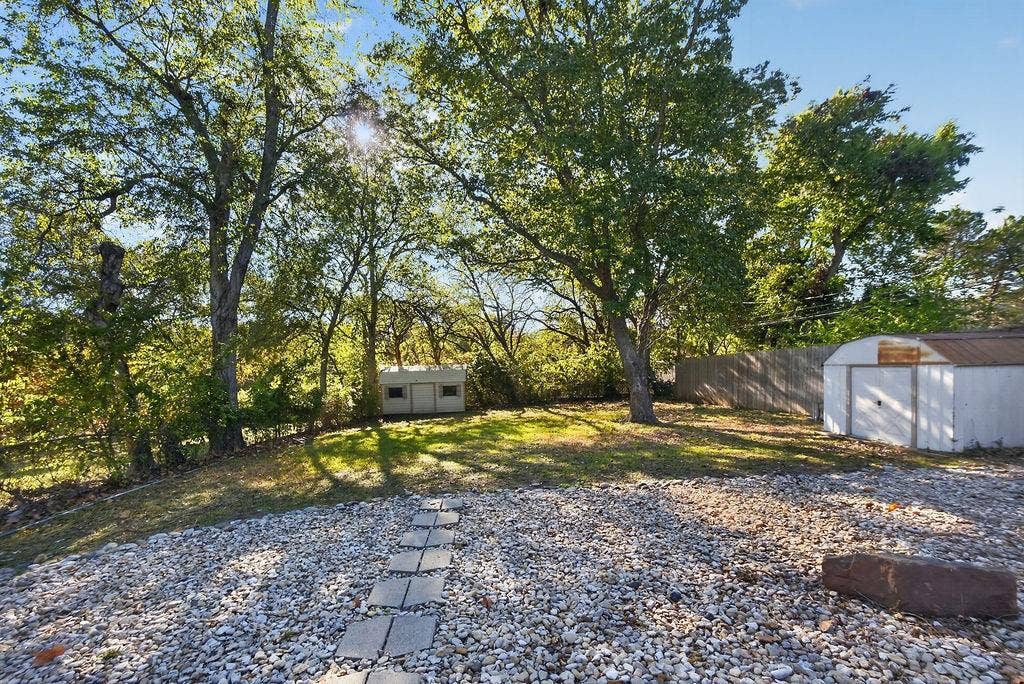 9112 Clearwater Drive, Dallas, TX 75243 Expansive yard featuring a gravel area, concrete stepping stones, and a sloped lawn