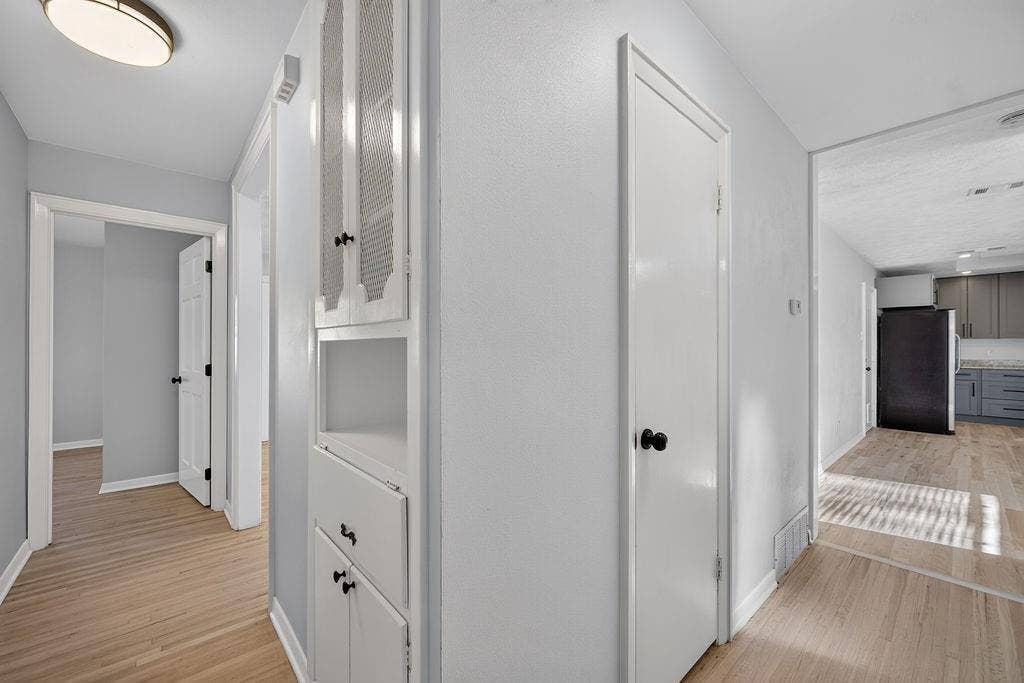 9112 Clearwater Drive, Dallas, TX 75243 Wood-finish flooring, built-in storage cabinetry, interior doors with black hardware, and an overhead light fixture