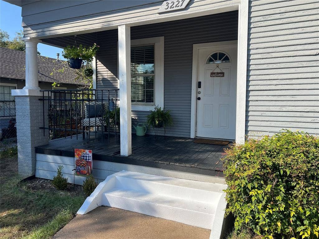 3227 Avenue I, Fort Worth, TX 76105 Covered front porch with white columns, gray siding, and a white entry door with an arched transom