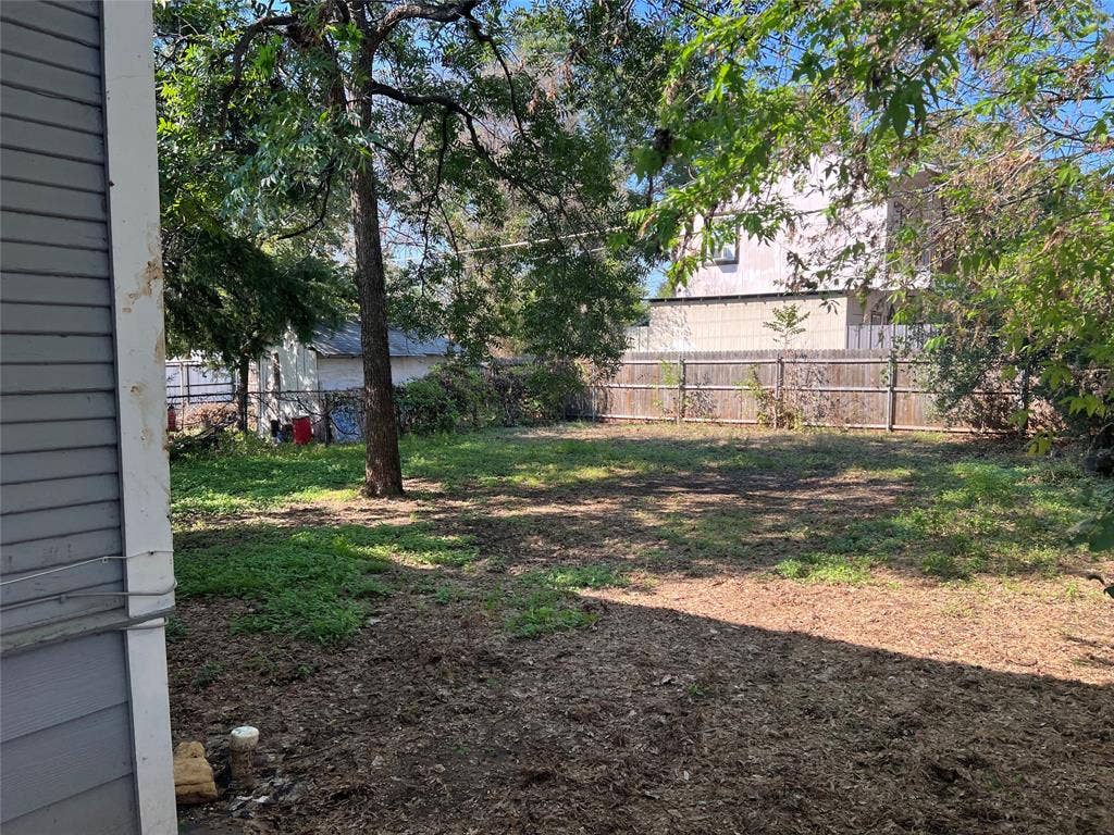 3227 Avenue I, Fort Worth, TX 76105 Expansive backyard featuring a mature tree, natural ground cover, and a wood privacy fence