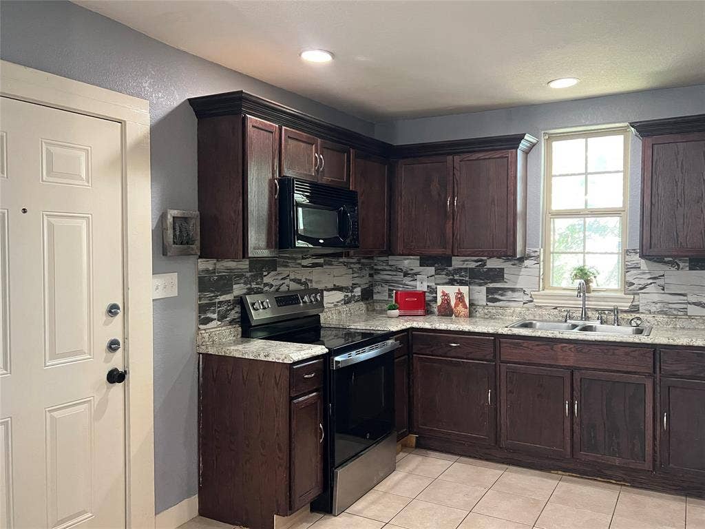 3227 Avenue I, Fort Worth, TX 76105 Kitchen featuring dark wood-finish cabinetry, light-colored countertops, stainless steel appliances, and a tiled backsplash