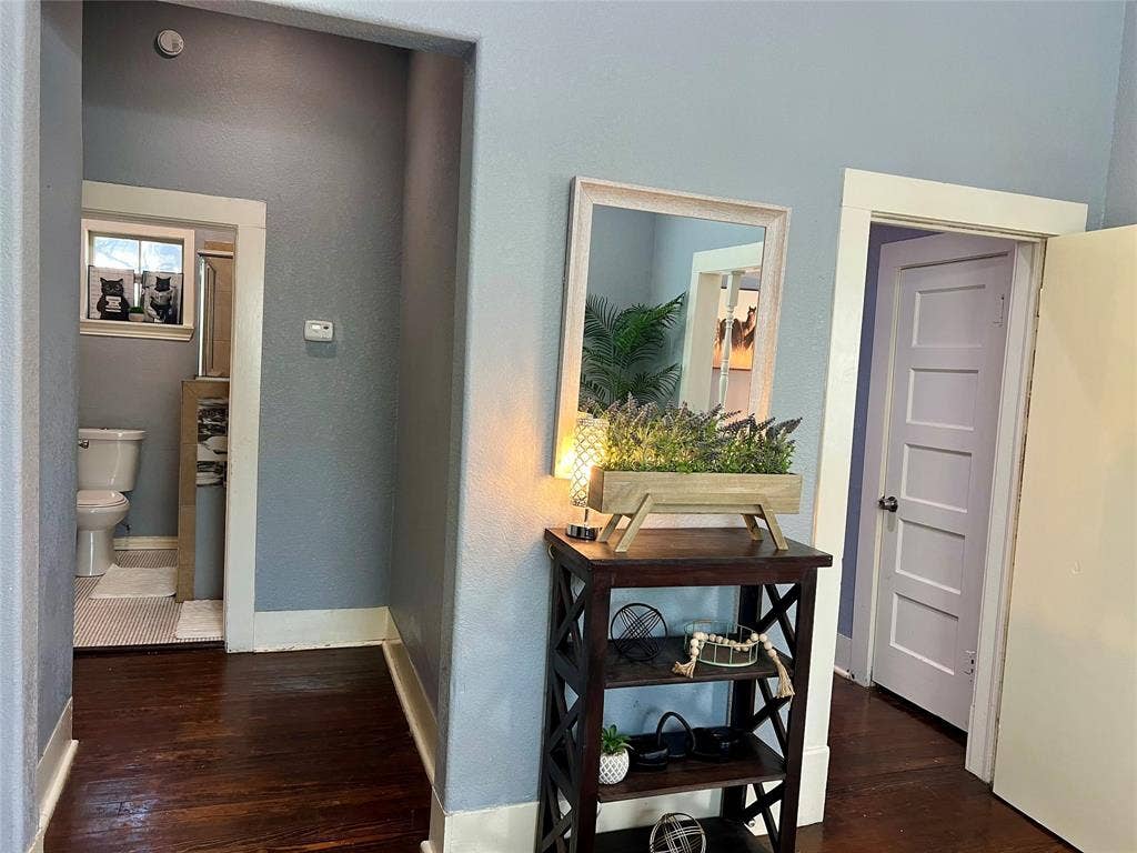 3227 Avenue I, Fort Worth, TX 76105 Dark wood-finish flooring with white trim, a toilet with a window, and a paneled interior door
