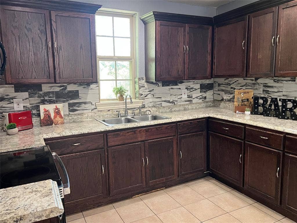 3227 Avenue I, Fort Worth, TX 76105 Wood-finish cabinetry paired with granite-patterned countertops and a tile backsplash