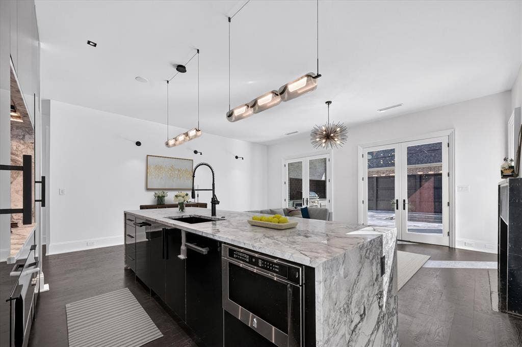 6404 Lakehurst Avenue, Dallas, TX 75230 Waterfall island with integrated sink and dishwasher, dark wood-finish flooring, white walls, recessed ceiling lighting, and double glass French doors