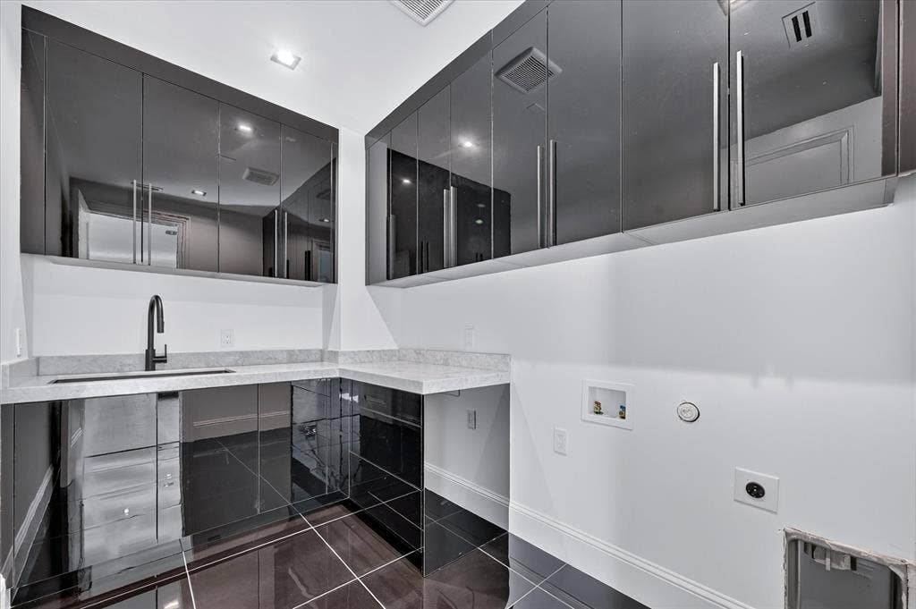 6404 Lakehurst Avenue, Dallas, TX 75230 Glossy black cabinetry, white countertops, built-in sink with a black faucet, and dark tile flooring