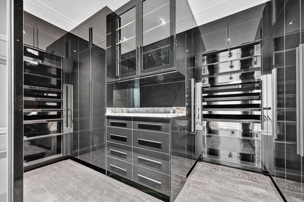 6404 Lakehurst Avenue, Dallas, TX 75230 Custom built-in cabinetry with glass-front uppers, a central vanity with a stone countertop, wood-finish flooring, and integrated display shelving
