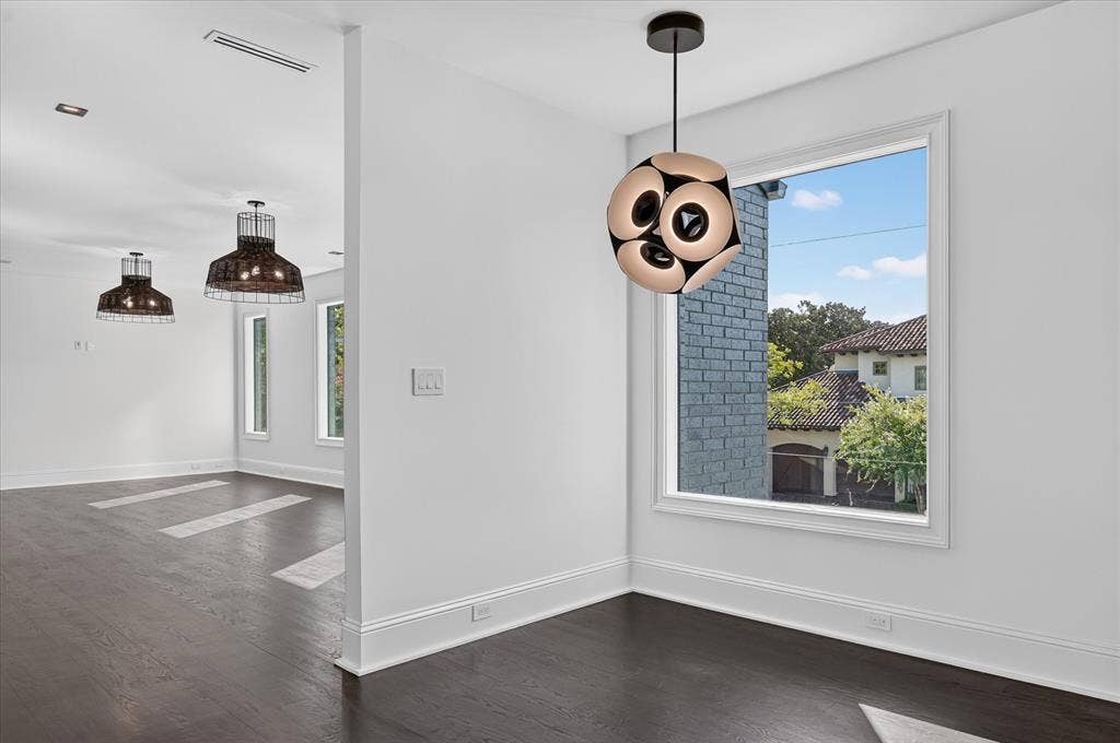6404 Lakehurst Avenue, Dallas, TX 75230 Bright, open kitchen and dining area featuring dark wood-finish flooring, white shaker cabinetry, and stainless steel pendant lighting