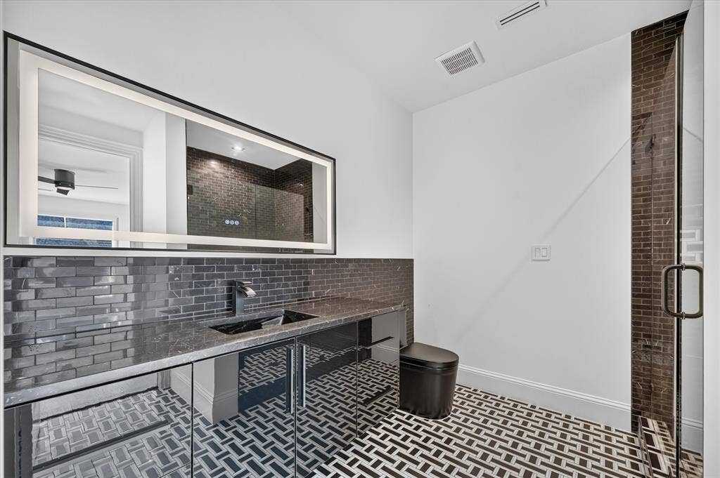 6404 Lakehurst Avenue, Dallas, TX 75230 Herringbone tile flooring, dual vessel sinks, and a large illuminated mirror