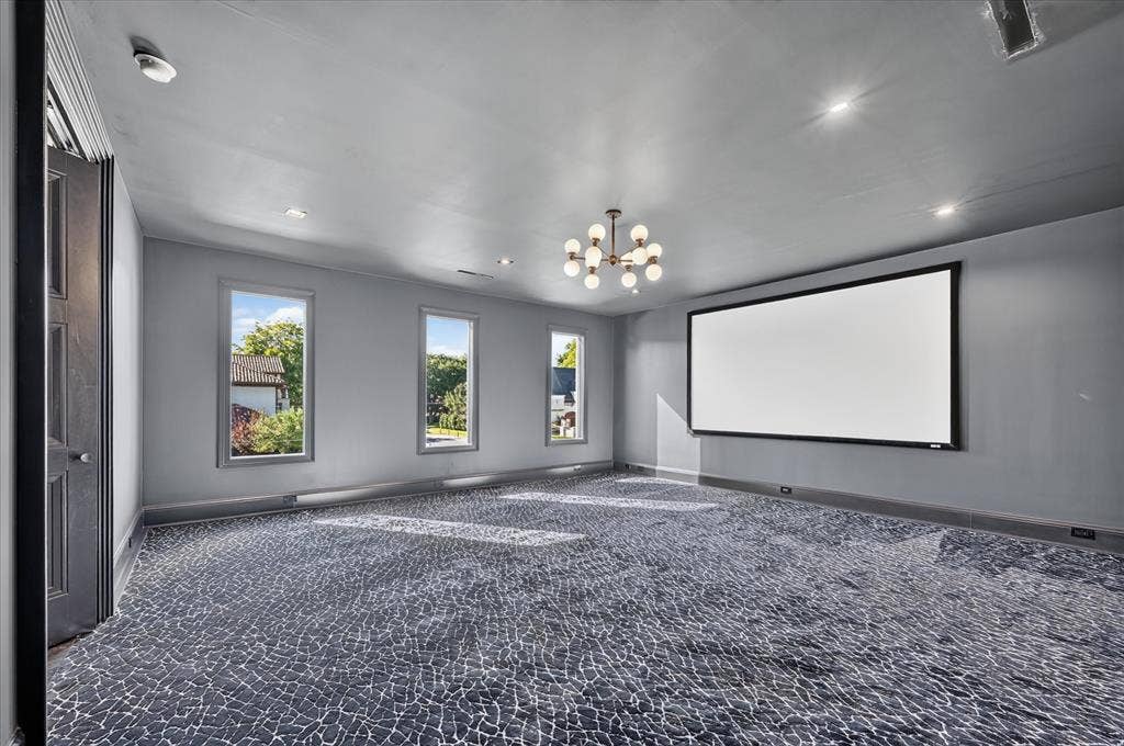 6404 Lakehurst Avenue, Dallas, TX 75230 Wall-mounted projection screen, patterned wall-to-wall carpeting, contemporary chandelier, recessed lighting, and multiple windows