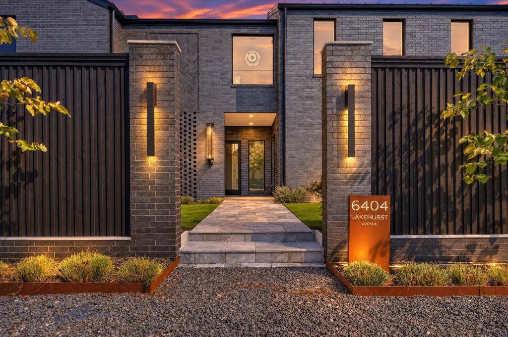 6404 Lakehurst Avenue, Dallas, TX 75230 Contemporary facade featuring dark brick, a stone walkway, and integrated exterior lighting