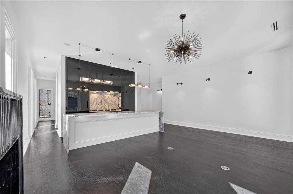 6404 Lakehurst Avenue, Dallas, TX 75230 Dark wood-finish flooring, a contemporary sputnik chandelier, and a built-in bar with stone finish countertop and backsplash