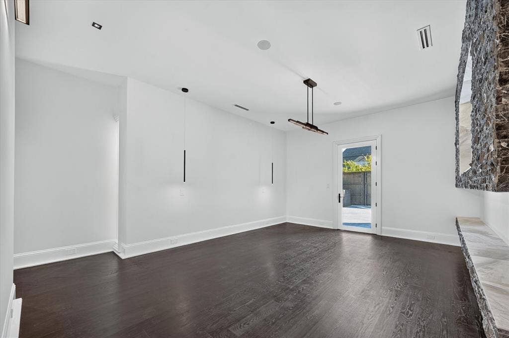 6404 Lakehurst Avenue, Dallas, TX 75230 Dark wood-finish flooring with white baseboards, a full-light exterior door, and a built-in stone feature with a stone ledge