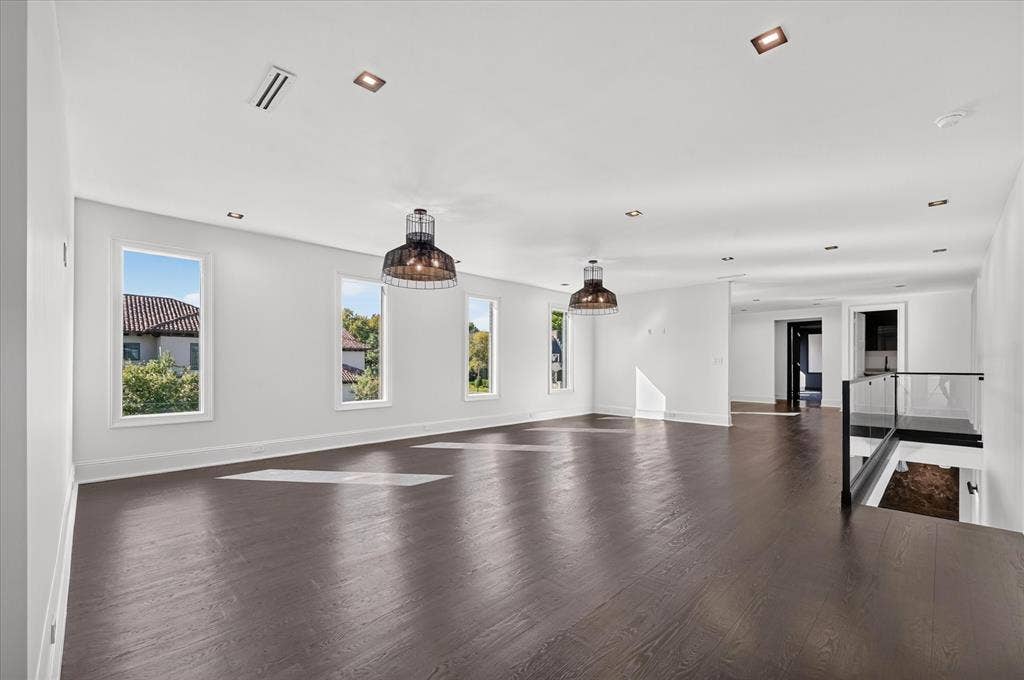 6404 Lakehurst Avenue, Dallas, TX 75230 Dark wood-finish flooring, recessed ceiling lighting, three tall windows, two pendant light fixtures, and a glass-paneled railing