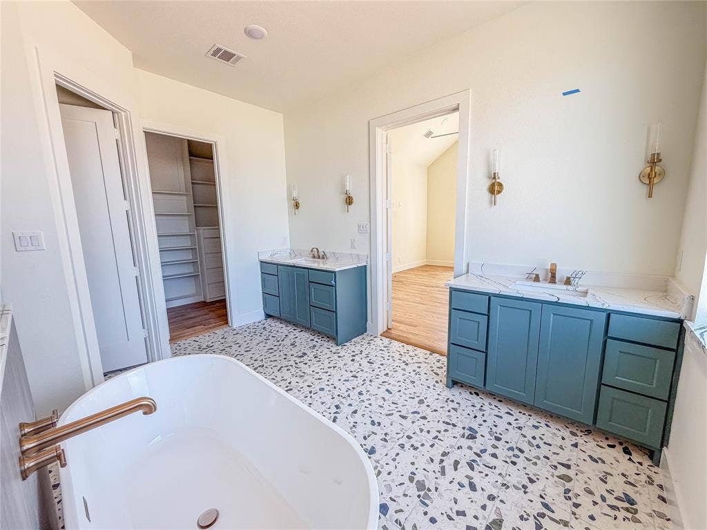 3860 Jacks Loop, Midlothian, TX 76065 Freestanding soaking tub with a bronze-finish faucet, dual vanity sinks with light-toned countertops, and built-in closet shelving