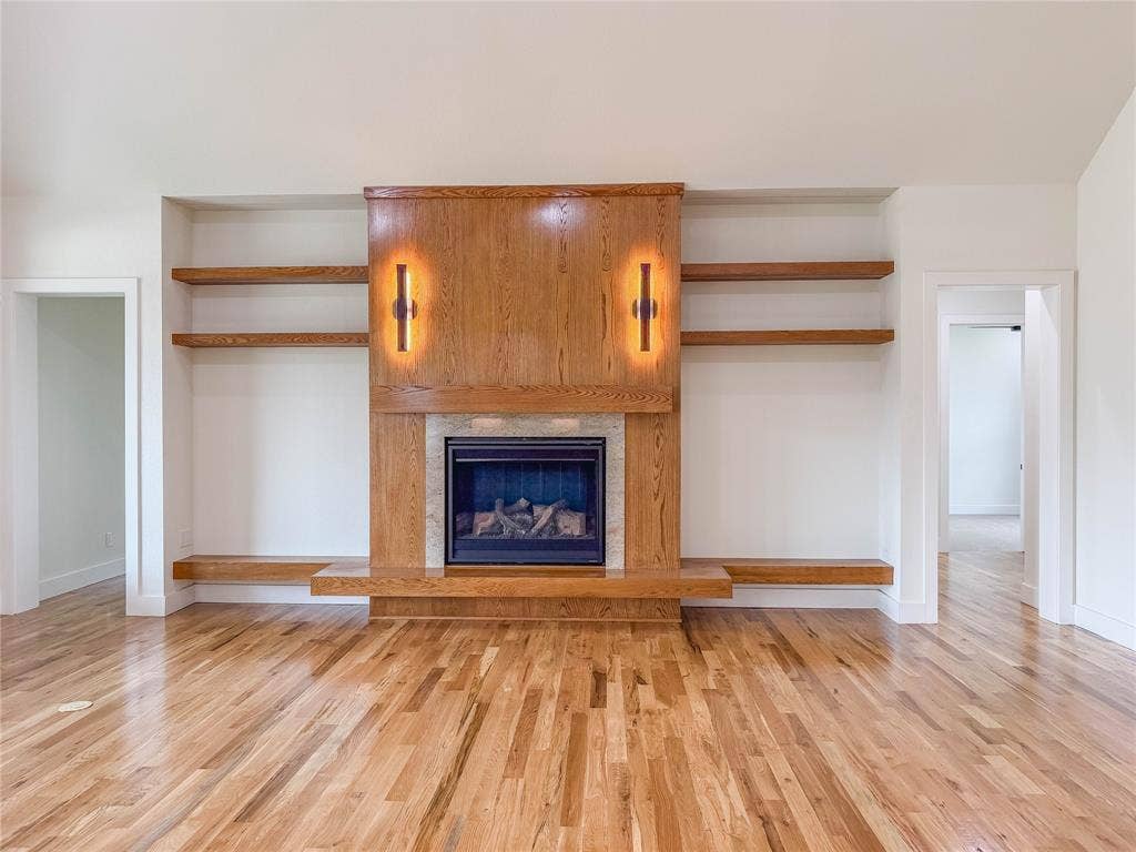 3860 Jacks Loop, Midlothian, TX 76065 Hardwood flooring, built-in shelving, stone fireplace surround, wood fireplace mantle, and integrated wall sconces
