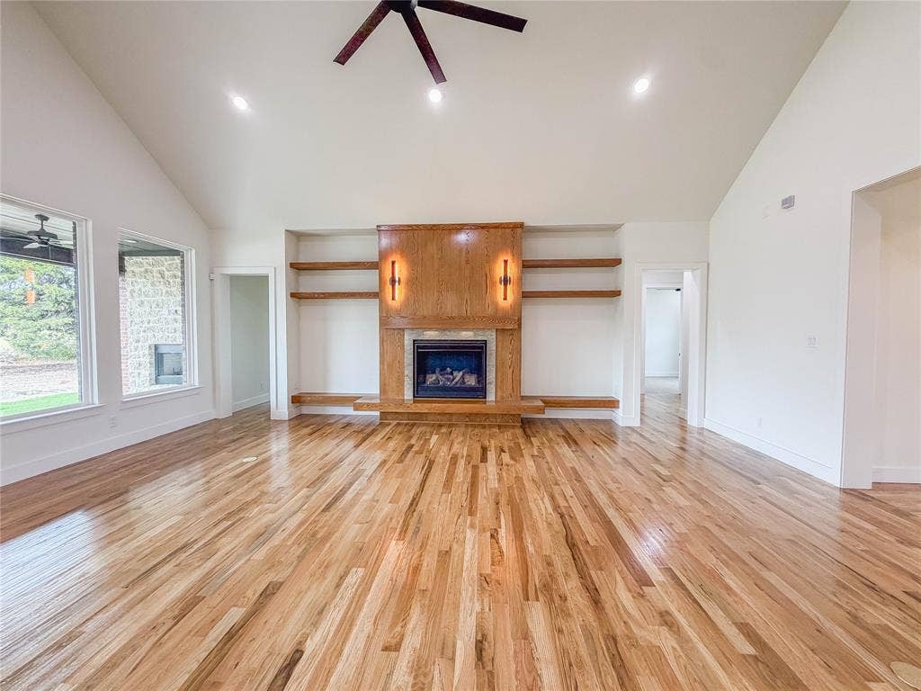 3860 Jacks Loop, Midlothian, TX 76065 Vaulted ceilings with recessed lighting, wood-finish flooring, a built-in fireplace with a wood-finish mantel and integrated shelving, and large windows