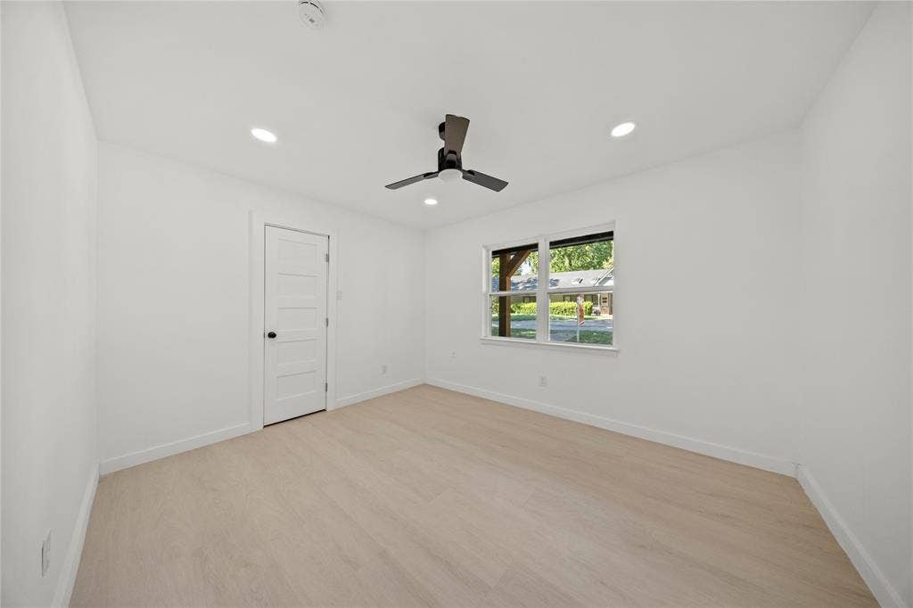 Interior room featuring neutral wall finishes, light-toned wood-finish flooring, a matte black ceiling fan, and a five-panel interior door