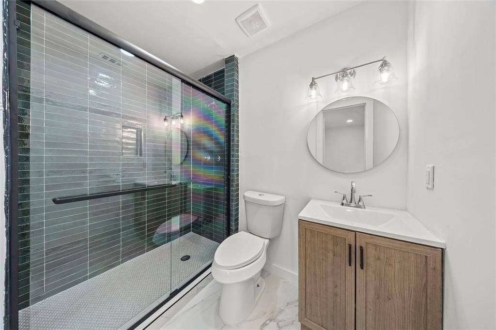 Walk-in shower with dark horizontal tile, glass enclosure, and white hexagonal floor tile