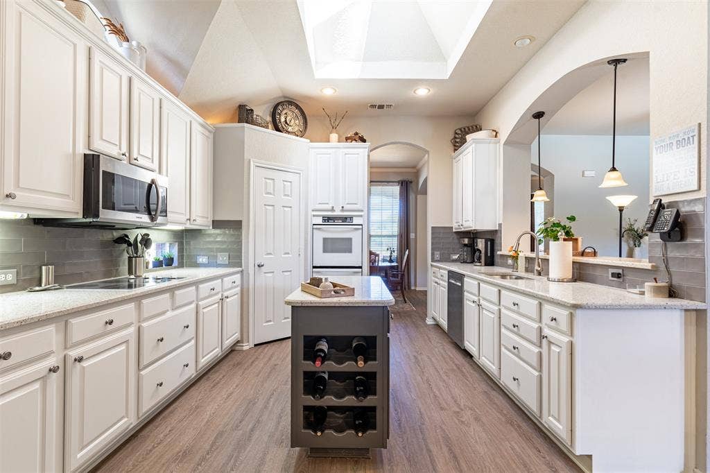 Kitchen features pristine white cabinetry with subway tile backsplash.