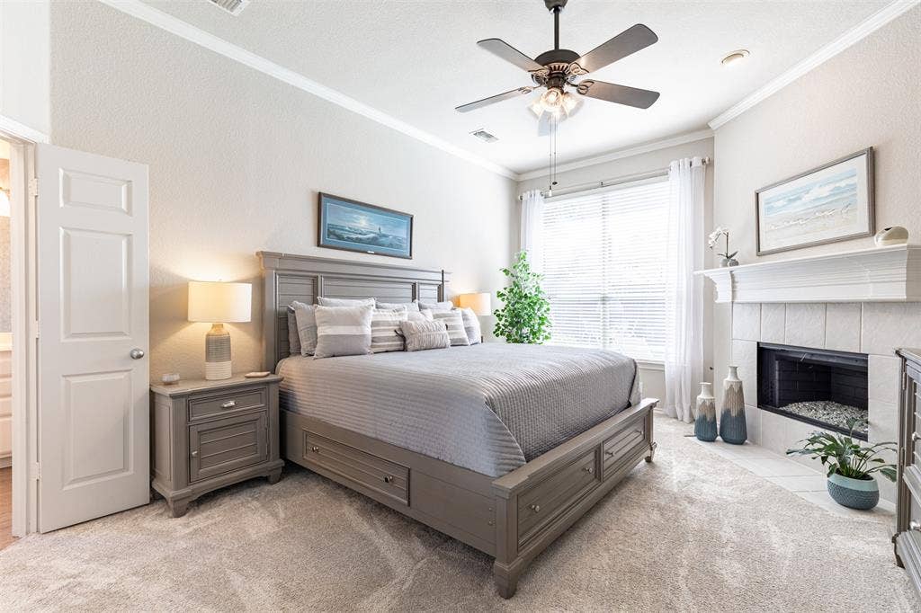 Primary suite with ceiling fan and fireplace with mantel.
