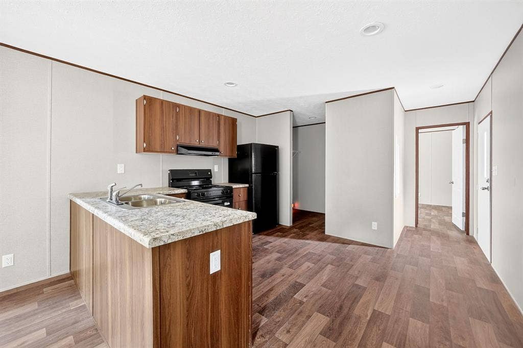 216 W Acres Road, Gun Barrel City, TX 75156 Kitchen featuring wood-finish cabinetry, a double basin stainless steel sink, black appliances, and light-colored countertops